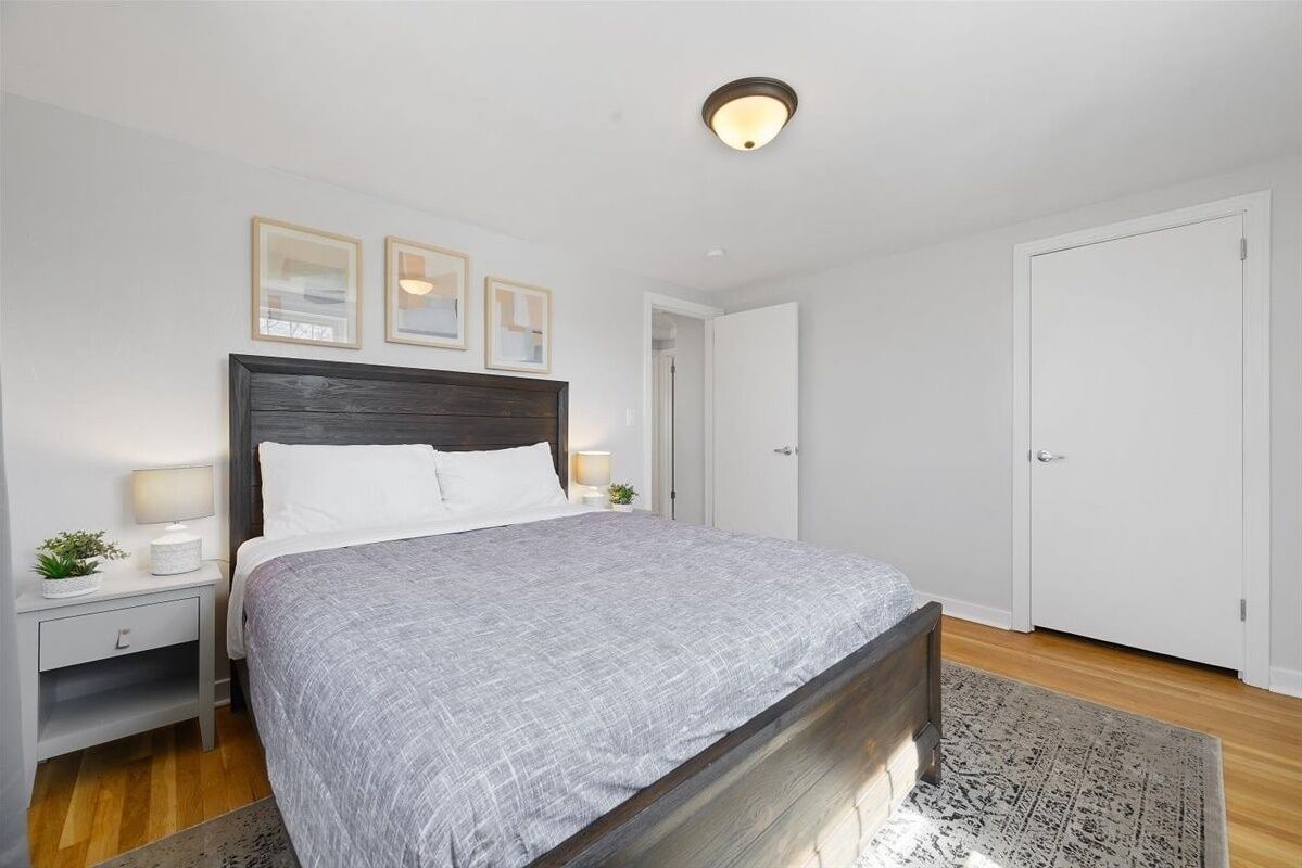 Een keurig opgemaakt slaapkamer met een bed, nachtkastjes en een deur.