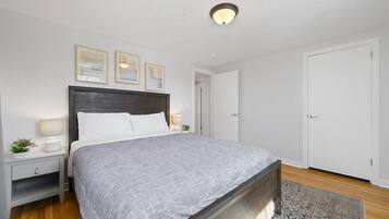 Een keurig opgemaakt slaapkamer met een bed, nachtkastjes en een deur.