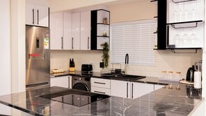 Eine moderne Küche mit Edelstahlkühlschrank, schwarzen Arbeitsplatten, weißen Schränken und einem eingebauten Backofen.