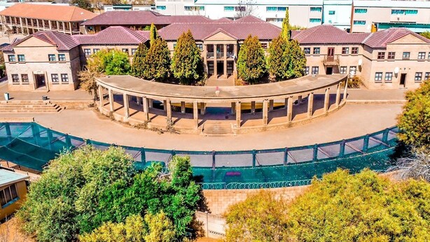 Un edificio circular con un espacio central abierto, rodeado de árboles y otros edificios.
