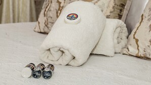 Una cama bien hecha con una toalla blanca doblada y una botella de loción.