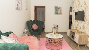 Una sala moderna con un sillón verde, un sofá rosa y una mesa de centro redonda.
