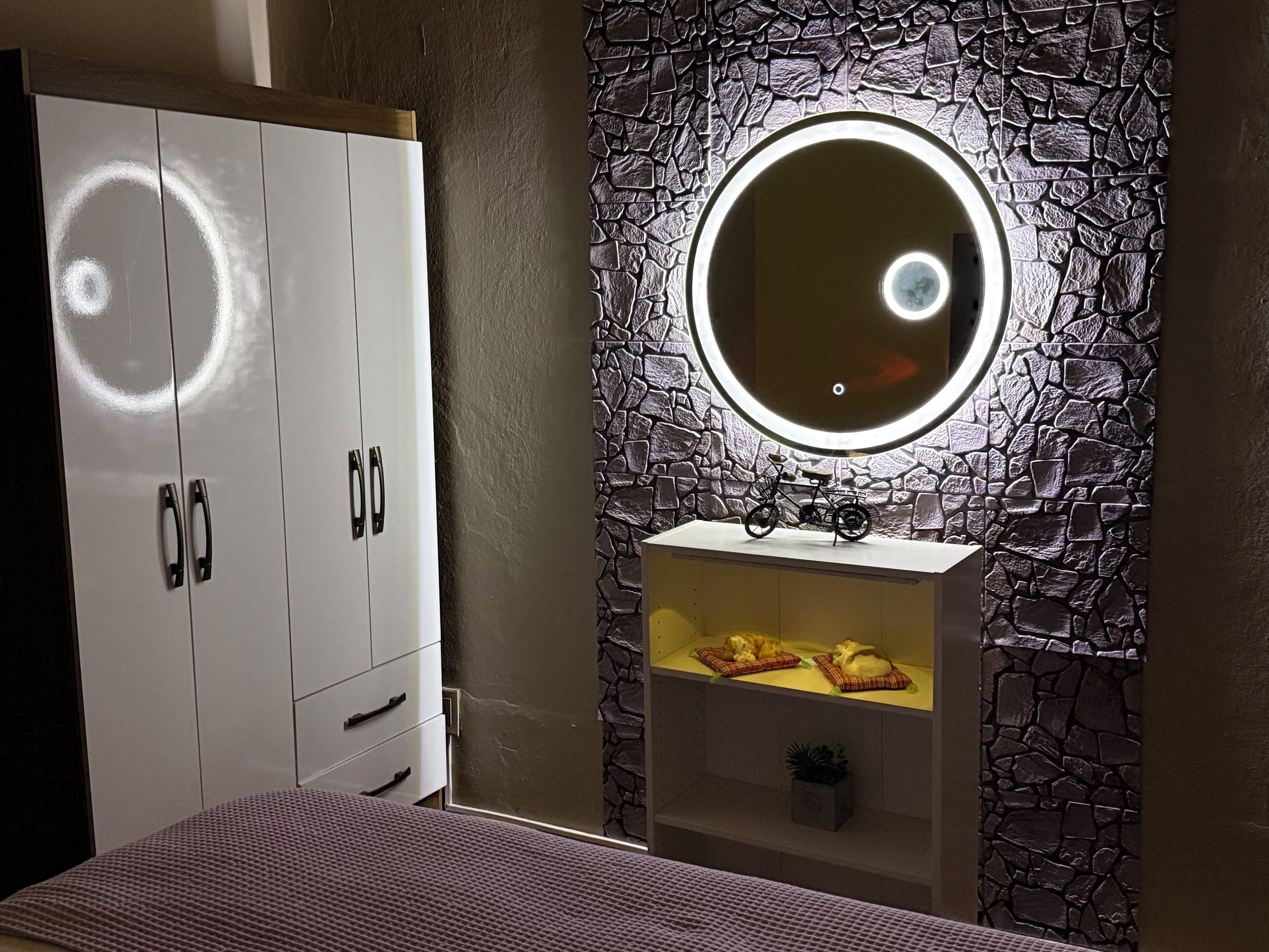Een slaapkamer met een garderobe, een spiegel en een plank met een fiets en kussens.