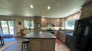 Une cuisine spacieuse avec des meubles en bois, un îlot central et un grand réfrigérateur.