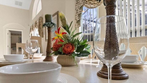 A dining table with a bowl, wine glass, and a vase with flowers. - Wookiee's Hideout - 4 bed private pool home in Cumbrian Lakes - 18 mins to WDW! (Kissimmee)