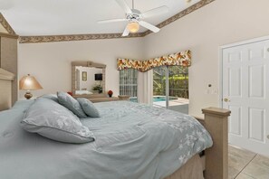 A bedroom with a bed, a ceiling fan, a large window with a view of a swimming pool, and a door. - Wookiee's Hideout - 4 bed private pool home in Cumbrian Lakes - 18 mins to WDW! (Kissimmee)