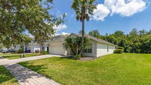 A single-story house with a paved driveway, a garage, and a well-maintained lawn. - Wookiee's Hideout - 4 bed private pool home in Cumbrian Lakes - 18 mins to WDW! (Kissimmee)