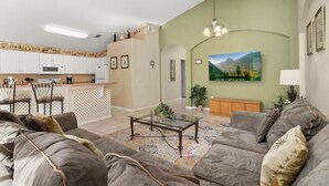 A living room with a sofa, coffee table, and a painting on the wall. - Wookiee's Hideout - 4 bed private pool home in Cumbrian Lakes - 18 mins to WDW! (Kissimmee)