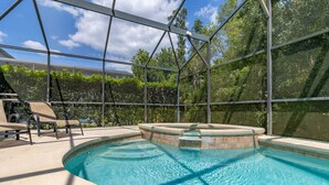 An indoor swimming pool with a glass enclosure, surrounded by lounge chairs and a view of trees. - Wookiee's Hideout - 4 bed private pool home in Cumbrian Lakes - 18 mins to WDW! (Kissimmee)