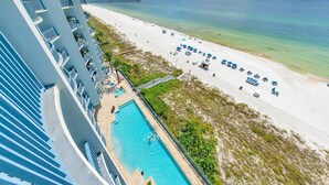 A hotel with a pool, beach, and ocean view.