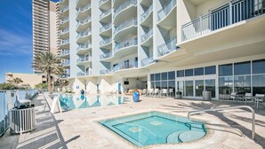 A hotel with a swimming pool, outdoor seating, and a multi-story building with balconies.