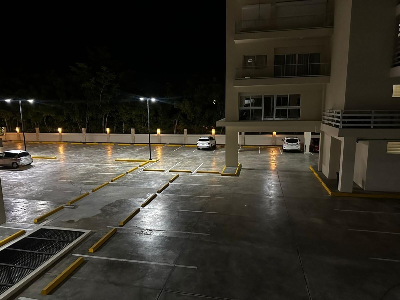 A multi-level parking garage with several cars parked, illuminated by overhead lights.