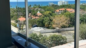 A balcony with a clear view of the ocean and surrounding buildings.