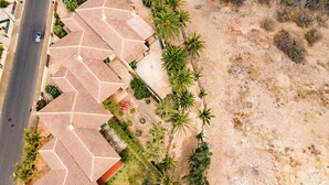 An aerial view of a residential area with multiple houses featuring red-tiled roofs, surrounded by palm trees and a sandy landscape. - House a few steps from the beach, Porto Santo (Porto Santo)