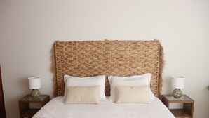 A bed with a woven headboard, two bedside tables with lamps, and two pillows. - House a few steps from the beach, Porto Santo (Porto Santo)