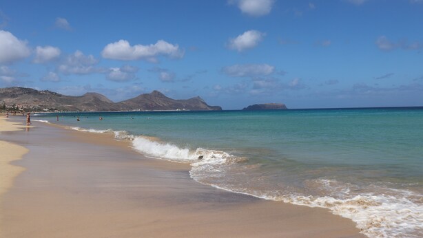 A beach with clear turquoise water, sandy shore, and distant mountains. - House a few steps from the beach, Porto Santo (Porto Santo)
