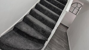 A staircase with carpeted steps leading to a landing. - Urban Hideaway Studio (London)