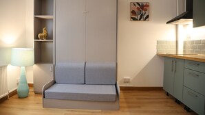 A compact kitchenette with a built-in seating area, a lamp, and a wall-mounted artwork. - Urban Hideaway Studio (London)