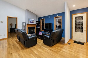 A living room with a fireplace, a television, and two leather sofas. - Serene Rustic Retreat with Lake (Cuddebackville)