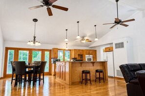 Una cocina amplia con armarios de madera, una isla central y un comedor con sillas.
