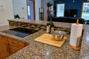 A kitchen with granite countertops, a built-in stove, a wooden cutting board, a metal bowl, and a roll of paper towels. - Serene Rustic Retreat with Lake (Cuddebackville)