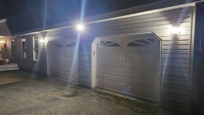 Een huis met twee garage deuren, een voortuin en een lamp aan de muur.