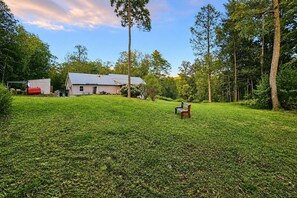 Un espacio al aire libre con césped, una banca y una casa al fondo.