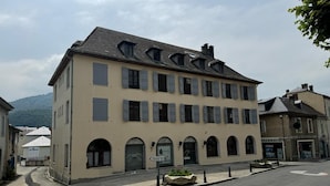 Ein mehrgeschossiges Gebäude mit einer symmetrischen Fassade, zahlreichen Fenstern und einem zentralen Eingang mit einem verzierten Bogen.
