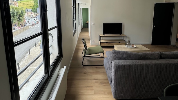 Ein modernes Wohnzimmer mit großem Fenster, einer Couch, einem Fernseher und einer Heizung.