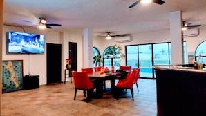 A spacious dining area with a high ceiling, multiple ceiling fans, and a large TV screen.