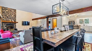 A spacious living area with a stone fireplace, a large wooden dining table, and a modern kitchen in the background. - Spacious Keystone Family Escape Great Location (Keystone)