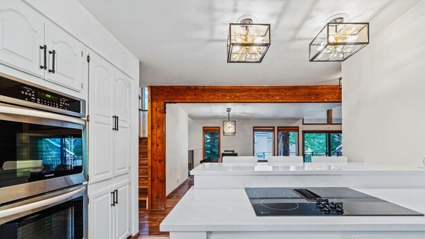 A modern kitchen with white cabinetry, stainless steel appliances, and a large island with a built-in stove. - Spacious Keystone Family Escape Great Location (Keystone)