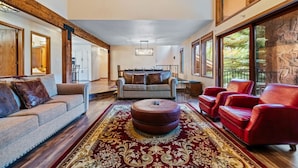 A spacious living room with a large rug, a sofa, a red leather chair, and a dining area with a table and chairs. - Spacious Keystone Family Escape Great Location (Keystone)
