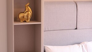 A bedroom with a bed, a wardrobe, and a shelf with a bottle and a golden figurine. - Stylish Studio Escape (London)