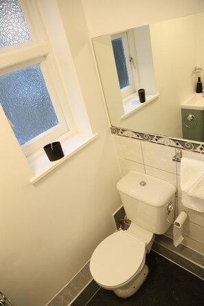 Un baño con inodoro, lavamanos, espejo y ventana.