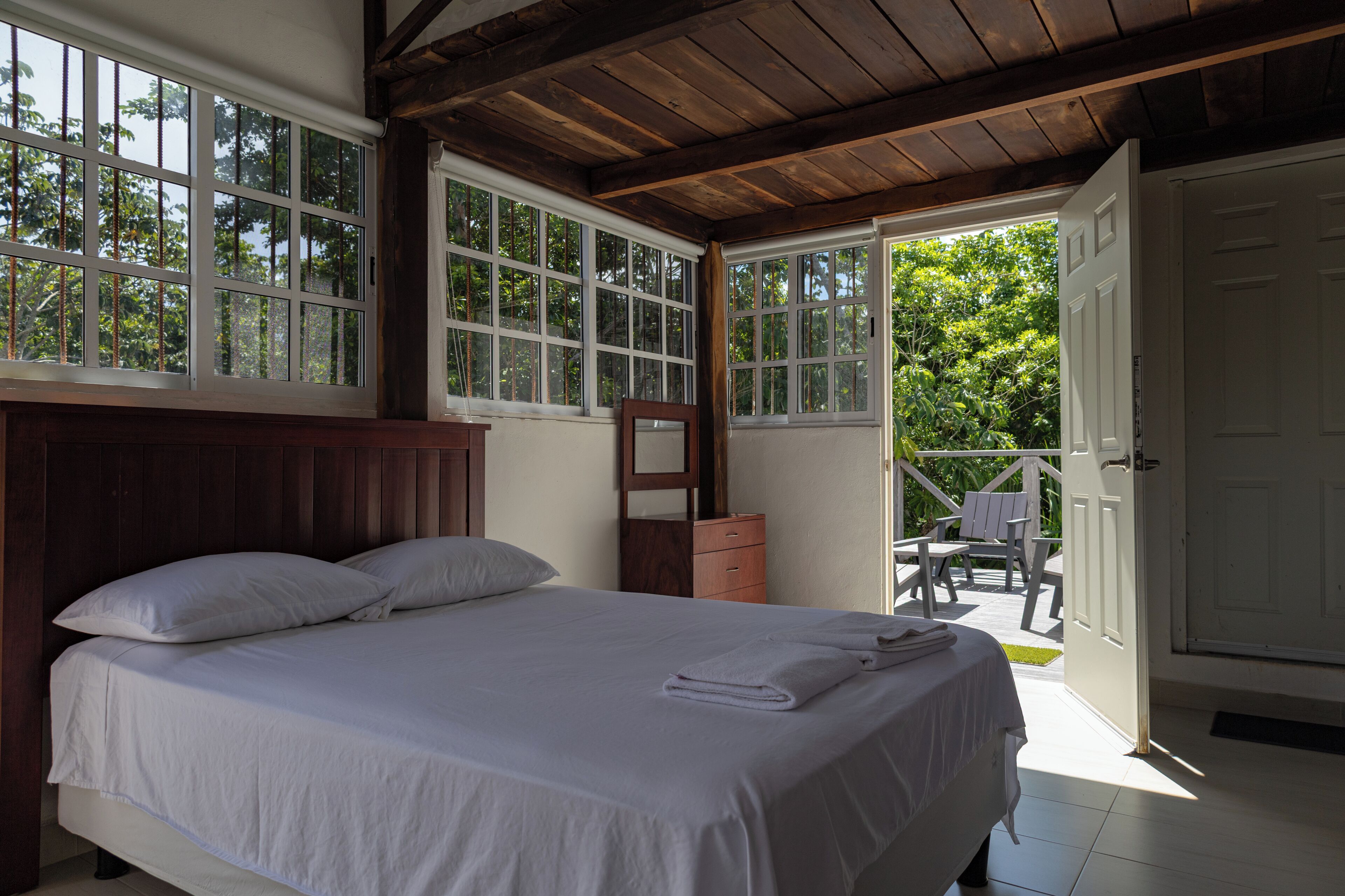 Un dormitorio con una cama grande, cabecera de madera y vistas al exterior a través de amplios ventanales.