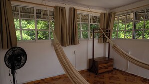 Een kamer met een hangmat, een ventilator en een houten dressoir.
