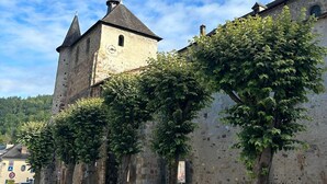 A historic stone building with a tower, ivy-covered walls, and a clear blue sky.