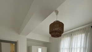 A bedroom with a large bed, a wardrobe, a wicker basket, and a hanging light fixture.