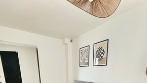 A modern living room with a grey sofa, a black dining table, and a wooden coffee table. There are two framed artworks on the wall.