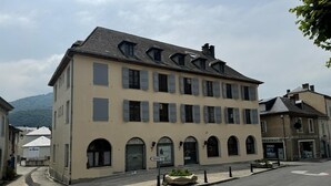 A multi-story building with a symmetrical facade, multiple windows, and a central entrance with a decorative archway.