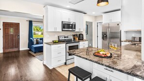 Una cocina moderna con armarios blancos, electrodomésticos de acero inoxidable y encimera de mármol.