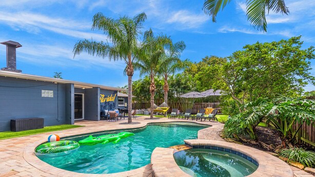 Un patio trasero con piscina, jacuzzi y mobiliario exterior.