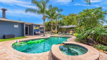 A backyard with a swimming pool, a hot tub, and outdoor seating.