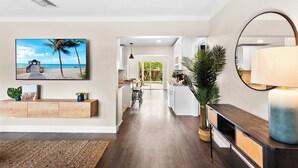 Una cocina moderna con armarios blancos, encimera de madera y una isla grande. Hay una zona de comedor con mesa y sillas, y vista al patio trasero a través de una puerta de cristal.