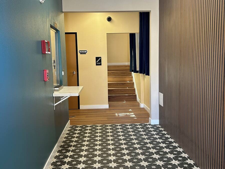 A hallway with a star-patterned floor, a staircase, and a sign indicating "Employee Only" access.
