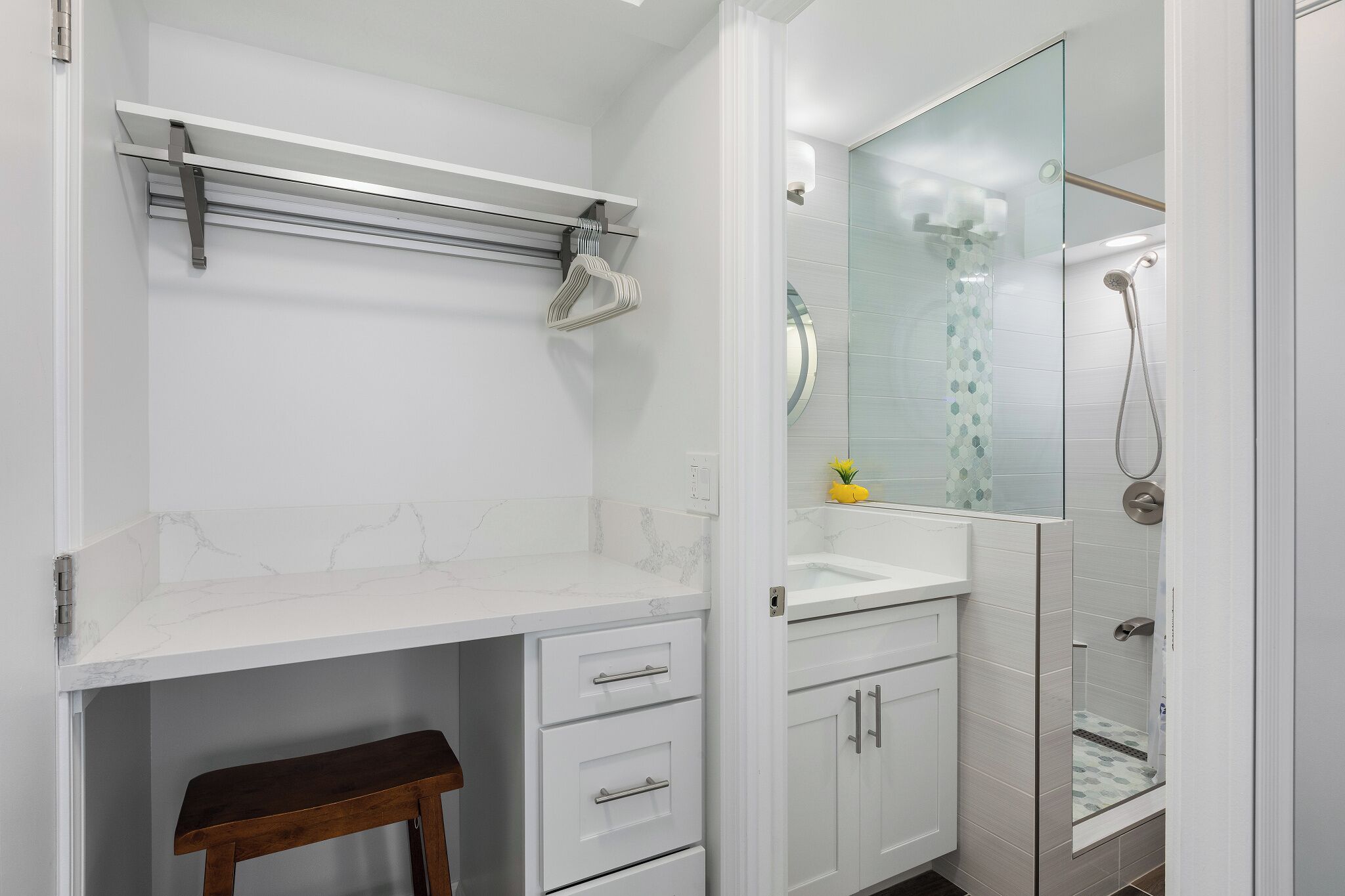 A modern bathroom with a white vanity, a glass shower enclosure, and a marble countertop.