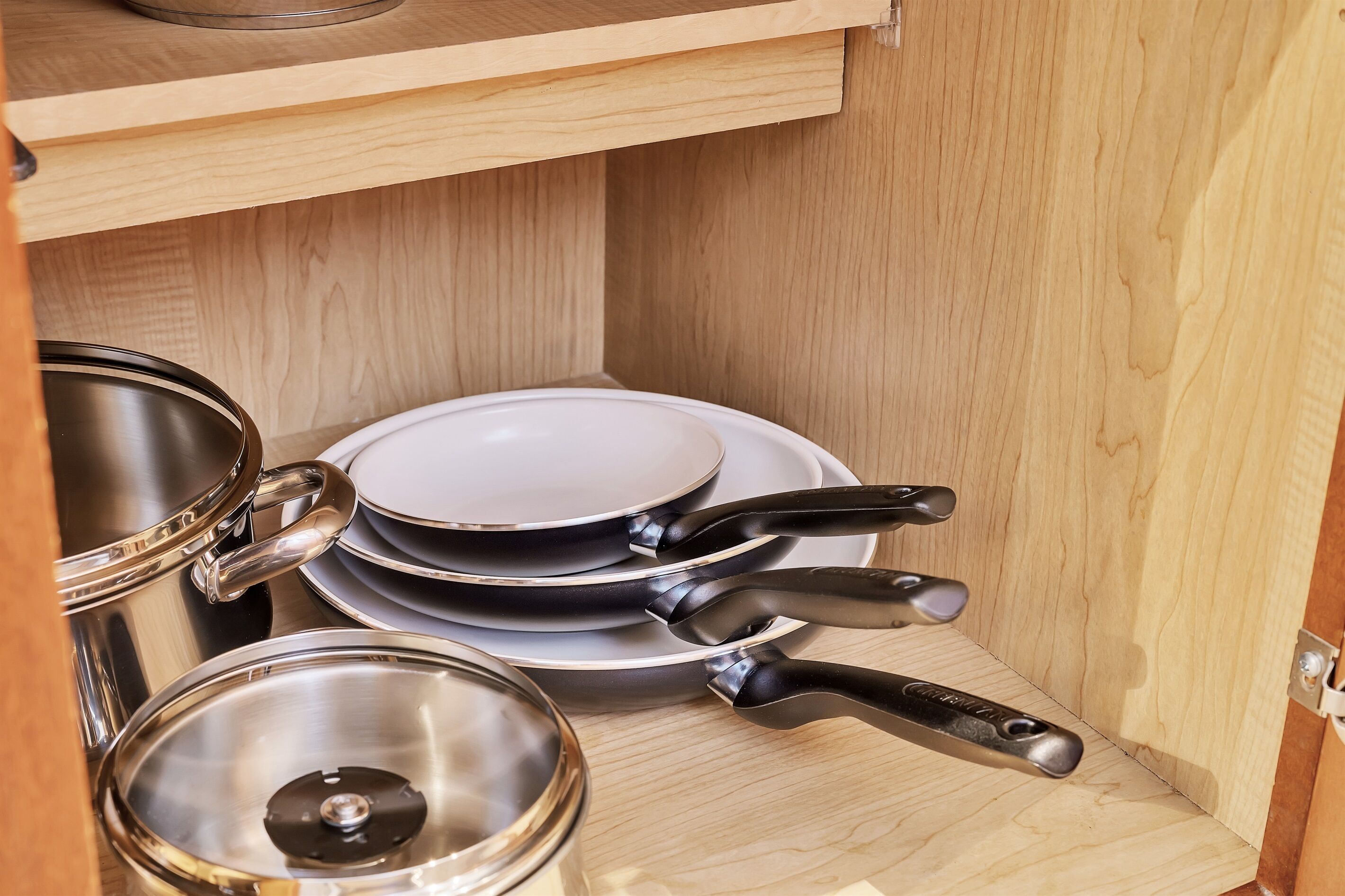 Un mueble de madera con utensilios de cocina y platos de acero inoxidable.