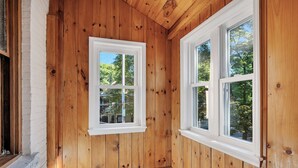 Ein Zimmer mit Holzwandverkleidung und zwei Fenstern mit weißen Rahmen.