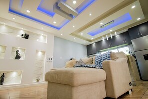 A modern living room with a sofa, a dining area with a refrigerator, and a kitchen with cabinets. - Spectacular and Modern Apartment with Jacuzzi (Santa Cruz Xoxocotlán)